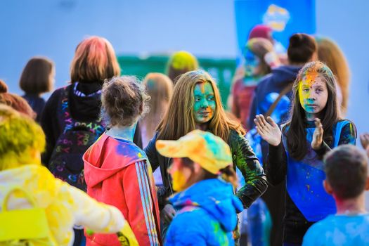 Russia, Moscow - June 25, 2017. Portrait of a girl with bright flowers on her face. Laughs with happiness. Holi is a traditional holiday in India