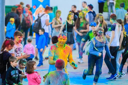 Russia, Moscow - June 25, 2017. Cheerful, young people throw themselves bright colors. Happy faces of adults and children are stained with paint. Holi is a traditional holiday in India