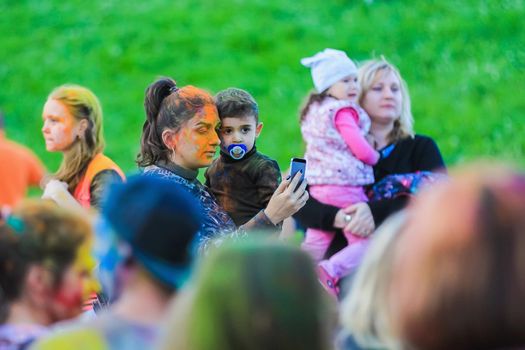 Russia, Moscow - June 25, 2017. Cheerful, young people throw themselves bright colors. Happy faces of adults and children are stained with paint. Holi is a traditional holiday in India