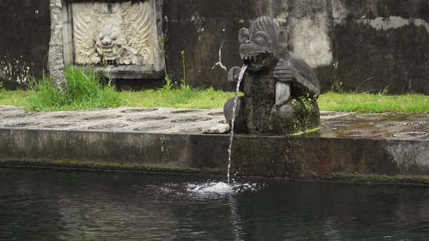 Hindu Balinese Water Palace Tirta Gangga with statues of the gods, fountains in the form of a wild boar on Bali island, Indonesia. Tirta Gangga the former royal water palace is a maze of pools and fountains surrounded by a lush garden and stone carvings and statues.