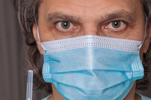 Adult man in a medical mask. Close-up eyes. Syringe in hand. Health safety concept