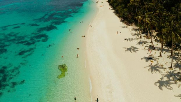 Tropical white sand beach, near the blue lagoon and corall reef from above, Boracay, Philippines. Sandy beach with tourists. Summer and travel vacation concept.