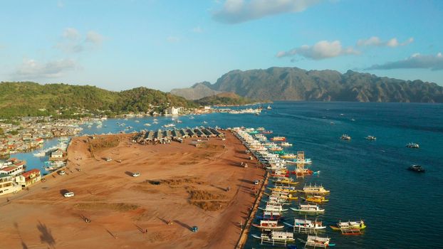 aerial view Pier and promenade Coron town with boats on Busuanga island. Wooden boats waiting at pier. Seascape with mountains. Philippines, Palawan