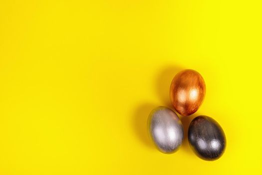 Easter. Multi-colored eggs on a uniform yellow background with place for text. View from above