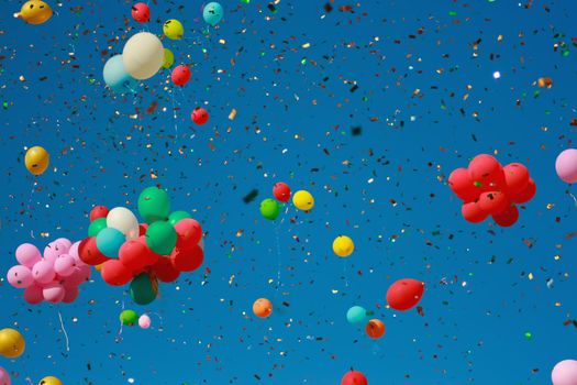 Multicolored glitter balloons launched into the blue sky. Celebration, birthday, balloons with helium.