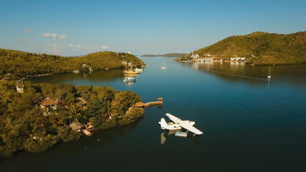 Aerial view: White Seaplane parked in the sea bay of the tropical island. Hydroplane in the lagoon and coastline. Philippines,Palawan, Busuanga. Travel concept