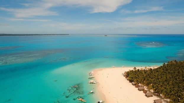 Aerial view of beautiful tropical island Daco with white sand beach. View of a nice tropical beach from the air. Beautiful sky, sea, resort. Seascape: Ocean and beautiful beach paradise. Philippines. Travel concept.
