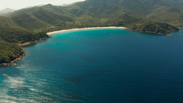 Aerial view beautiful tropical beach Nagtabon in the cove with blue lagoon and turquoise water surrounded by rainforest. Palawan, Philippines. tropical landscape. Seascape island and clear blue water. Summer and travel vacation concept