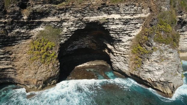 Aerial view of Rocky coast with high cliffs, sea surf with breaking waves on the coast, Nusa Penida, Indonesia. Ocean with waves and rocky cliff. Travel concept
