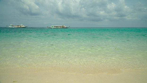 Tropical beach with boats and yachts on a background of sky and clouds. Summer and travel vacation concept.