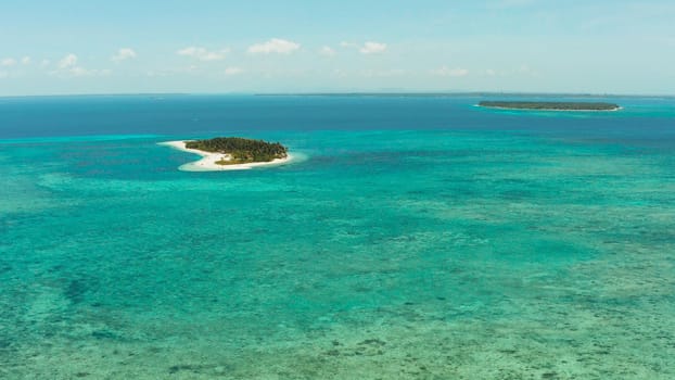 Small tropical island in the blue sea with a coral reef and the beach, top view. Summer and travel vacation concept. Canimeran Island, Balabac, Palawan, Philippines.