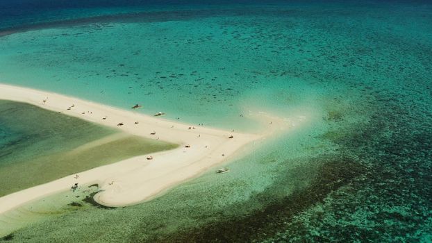 Beautiful beach on tropical island surrounded by coral reef, sandy bar with tourists, top view. Sandbar Atoll. Summer and travel vacation concept, Camiguin, Philippines.
