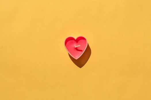 heart-shaped candle on a yellow background. isolate. place for the label. High quality photo