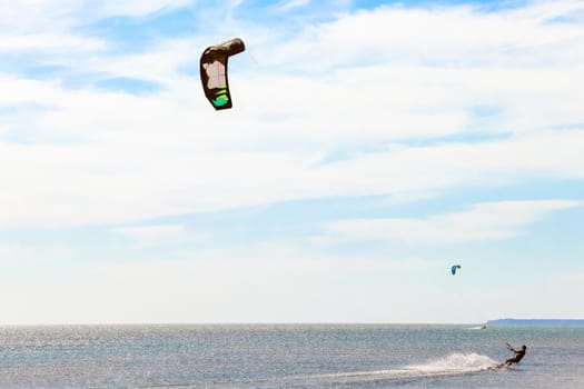 a kitesurfer surfing on the smooth azure water. recreational sport. A Man Rides A Kiteboarding In The Sea Water. extreme sport. High quality photo