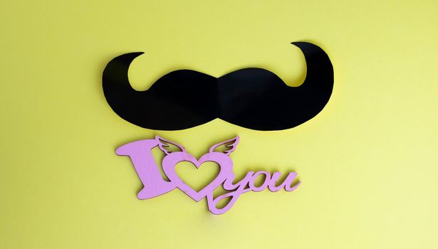 Father's Day concept. Black mustache and I love you sign on yellow paper background.