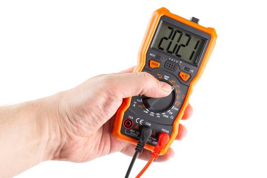 digit 2021 on lcd screen of digital electrical multimeter in left caucasian hand, isolated on white background