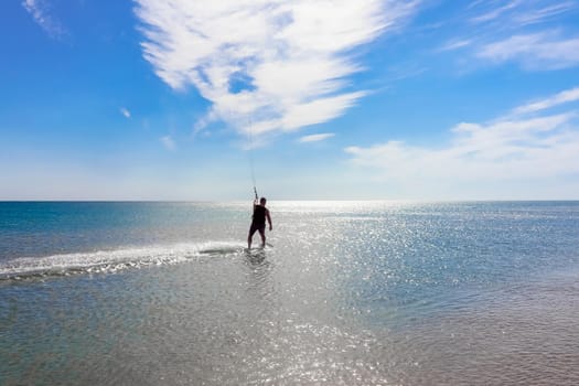 a kitesurfer surfing on the smooth azure water. recreational sport. A Man Rides A Kiteboarding In The Sea Water. extreme sport. High quality photo