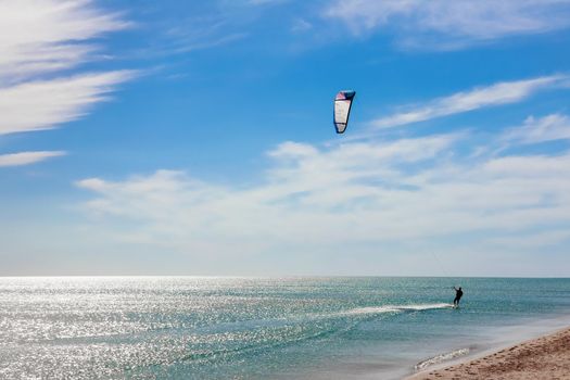 a kitesurfer surfing on the smooth azure water. recreational sport. A Man Rides A Kiteboarding In The Sea Water. extreme sport. High quality photo