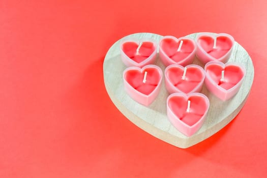 pink candles in the form of a heart on a red background for Valentine's day . High quality photo