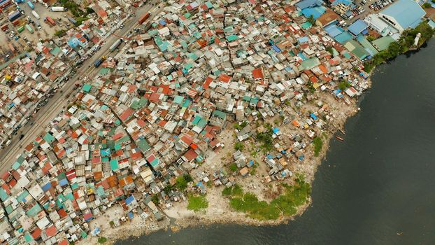 Slums with shacks of local residents and the river bank littered with garbage from above. Manila, Philippines.