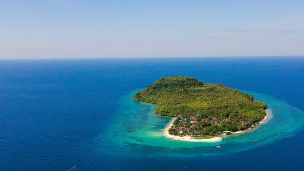 Himokilan Island, Leyte Island, Philippines. Tropical island with a village and a white beach. Turquoise water and coral reefs around the island. Summer holiday vacation concept.