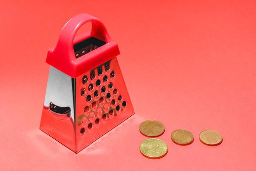 kitchen grater on a red background with Euro coins. High quality photo