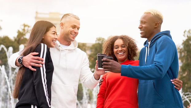 Multi-ethnic group teenage friends. African-american asian caucasian student spending time together Multiracial friendship Happy smiling People dressed colorful sportswear drink coffee outdoor