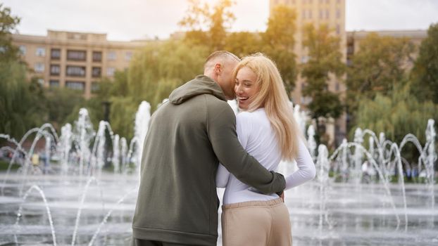 Couple in love walking outdoors park fountain Caucasian man woman walk outside after jogging dressed sport clothes Healthy livestyle Rear view