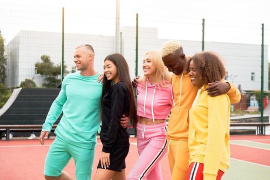 Multi-ethnic group teenage friends. African-american asian caucasian student spending time together Multiracial friendship Happy smiling People dressed colorful sportswear meeting outdoor sportground