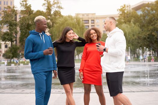 Multi-ethnic group teenage friends. African-american asian caucasian student spending time together Multiracial friendship Happy smiling People dressed colorful sportswear drink coffee outdoor