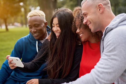 Multi ethnic friends outdoor looking smartphone screen. Diverse group people Afro american asian caucasian spending time together Multiracial male female student sitting bench park outdoors