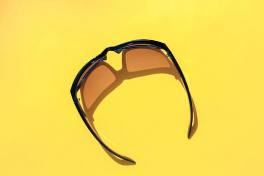 sunglasses on a yellow background. hard shadow. isolate. High quality photo