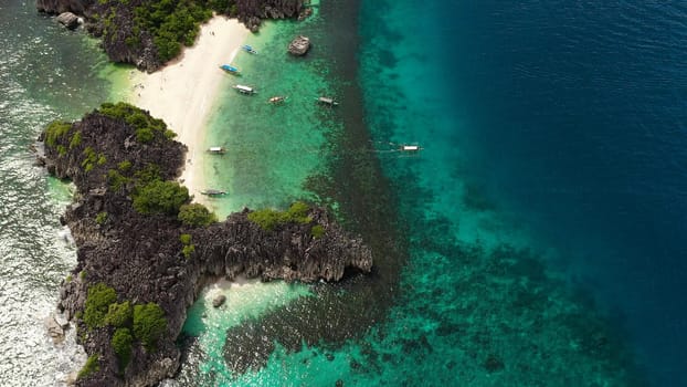 Tropical beach with tourists surrounded by blue water, aerial view. Lahos Island, Caramoan Islands, Philippines. Summer and travel vacation concept.