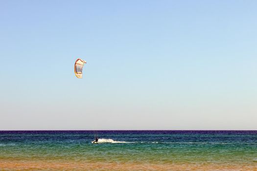 a kitesurfer surfing on the smooth azure water. recreational sport. A Man Rides A Kiteboarding In The Sea Water. extreme sport. High quality photo