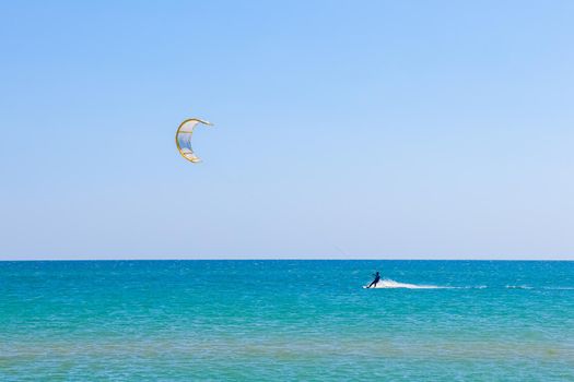 a kitesurfer surfing on the smooth azure water. recreational sport. A Man Rides A Kiteboarding In The Sea Water. extreme sport. High quality photo