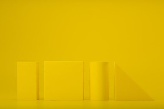 Yellow geometric figures against yellow background with copy space