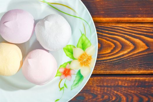 colorful marshmallows on a plate on a wooden background. High quality photo