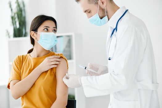 patient in a medical mask looks at the doctor with a syringe in hand vaccination. High quality photo