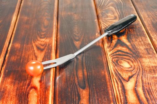 fork with a tomato on a wooden background. High quality photo