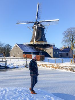 Pelmolen Ter Horst, Rijssen Netherlands during snowy weather snow covered wind mill in the netherlands, men walking in the snow in the Netherlands by historical windmill