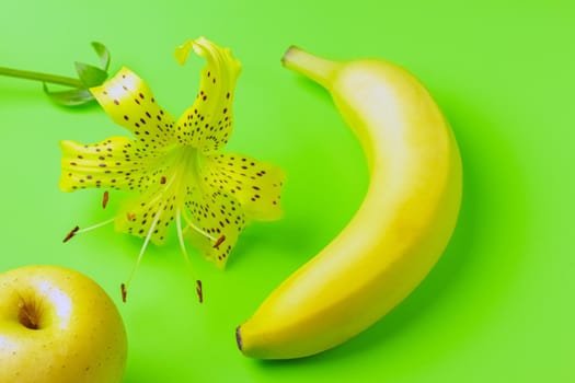 tiger Lily with banana and Apple on a green background close-up. isolate. High quality photo