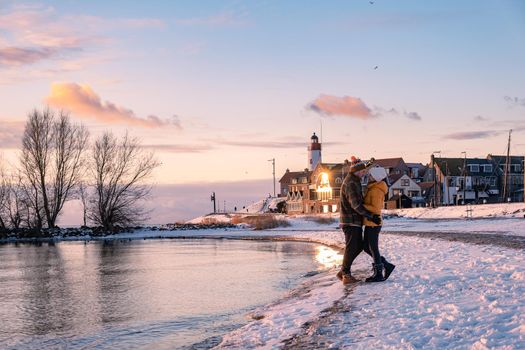 couple men and woman by the lighthouse of Urk Netherlands during winter in the snow. Winter weather in the Netherlands by Urk