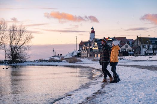 couple men and woman by the lighthouse of Urk Netherlands during winter in the snow. Winter weather in the Netherlands by Urk