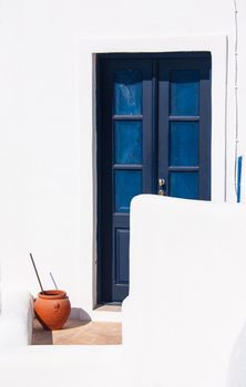 blue door of white Santorini Greek house with flower pot on stairs. City of Oia, Santorini, Greece