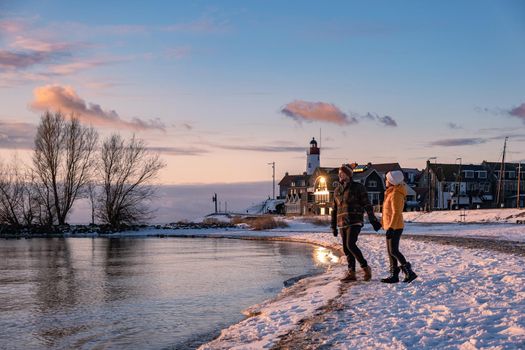 couple men and woman by the lighthouse of Urk Netherlands during winter in the snow. Winter weather in the Netherlands by Urk