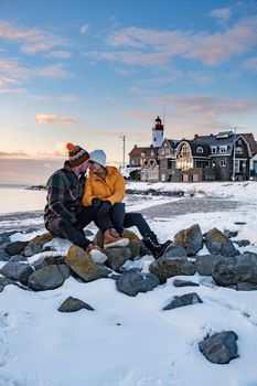 couple men and woman by the lighthouse of Urk Netherlands during winter in the snow. Winter weather in the Netherlands by Urk
