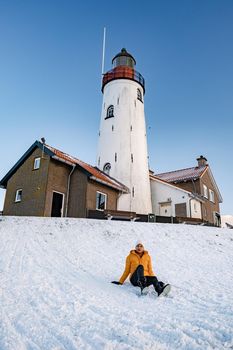 woman by the lighthouse of Urk Netherlands during winter in the snow. Winter weather in the Netherlands by Urk