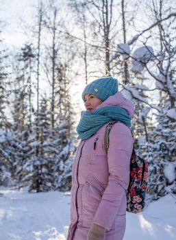 A girl in a red jacket walks through a snow-covered forest on a winter day. A woman admires the winter nature. A man on the background of beautiful winter nature