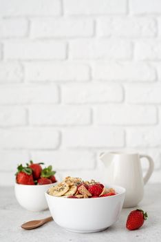 Healthy eating and dieting. Healthy breakfast, cereal, fresh berries and milk in a bowl on white brick wall background, copy space