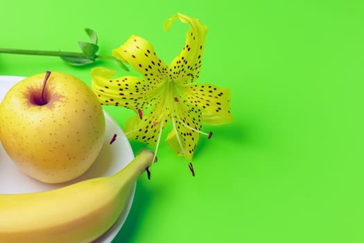 tiger Lily with banana and Apple on a green background close-up. isolate. High quality photo